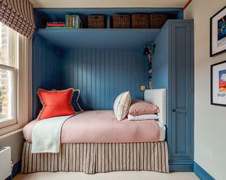 small guest bedroom with blue painted alcove and above storage bed