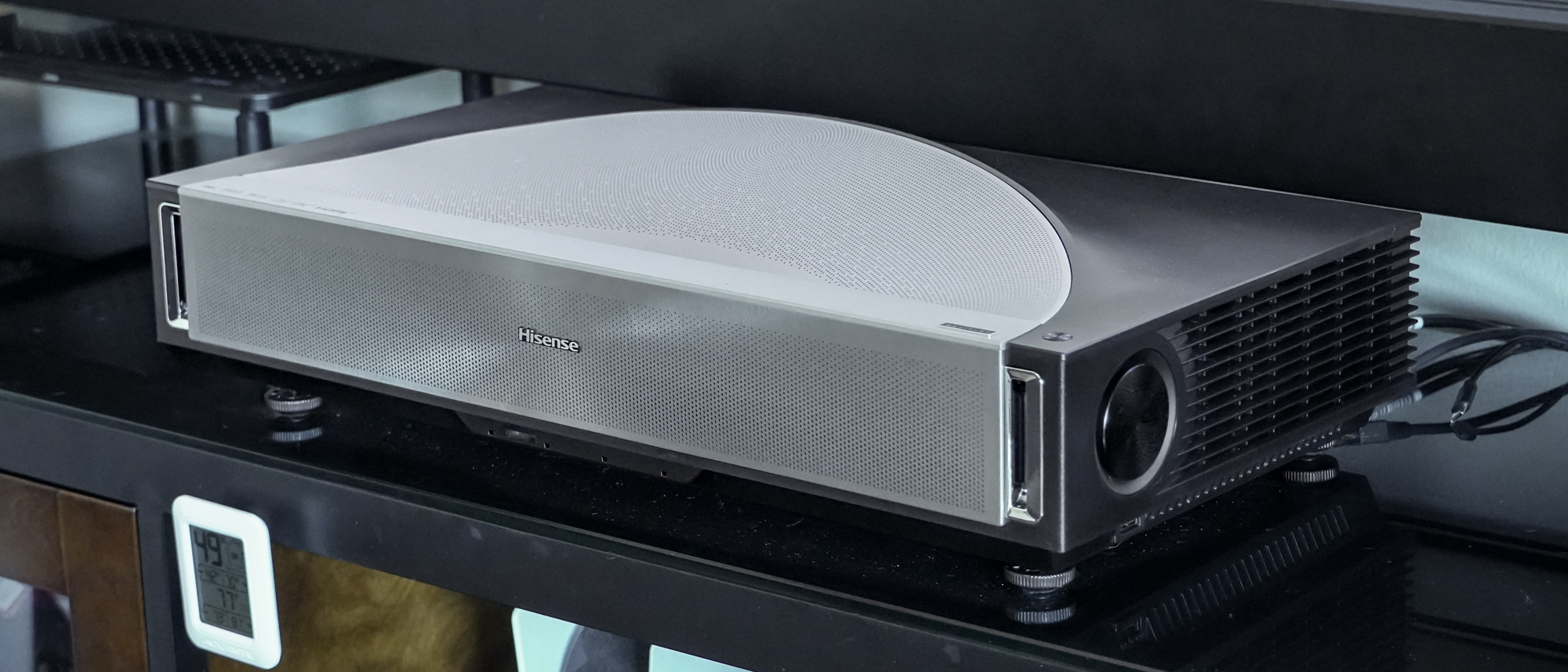 A Hisense PX4 Pro projector on a home media center shelf