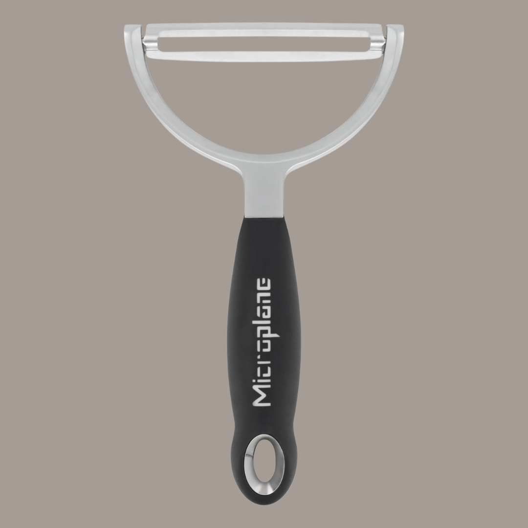 Microplane Professional XL Peeler in black plastic and stainless steel against dark brown background.