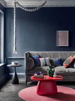 Grey living room walls with a grey sofa and a red coffee table