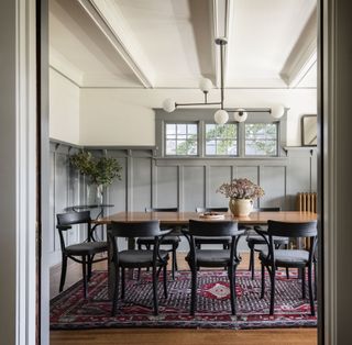 A neutral gray painted Arts & Crafts-wainscoting wraps around a modern dining room