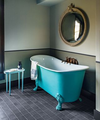 Bathroom with aqua painted slipper bath, black tiled floor and antique convex round mirror
