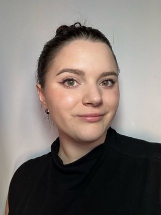 Brooke Knappeneber, marie claire associate commerce editor headshot in black shirt against grey background hair up