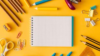 Back to school themed image with stationary and notepad on yellow desktop