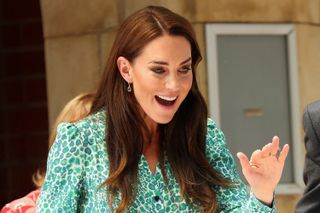 Kate Middleton smiling and waving in a green dress