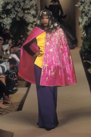 Model on catwalk wearing pink starred cape