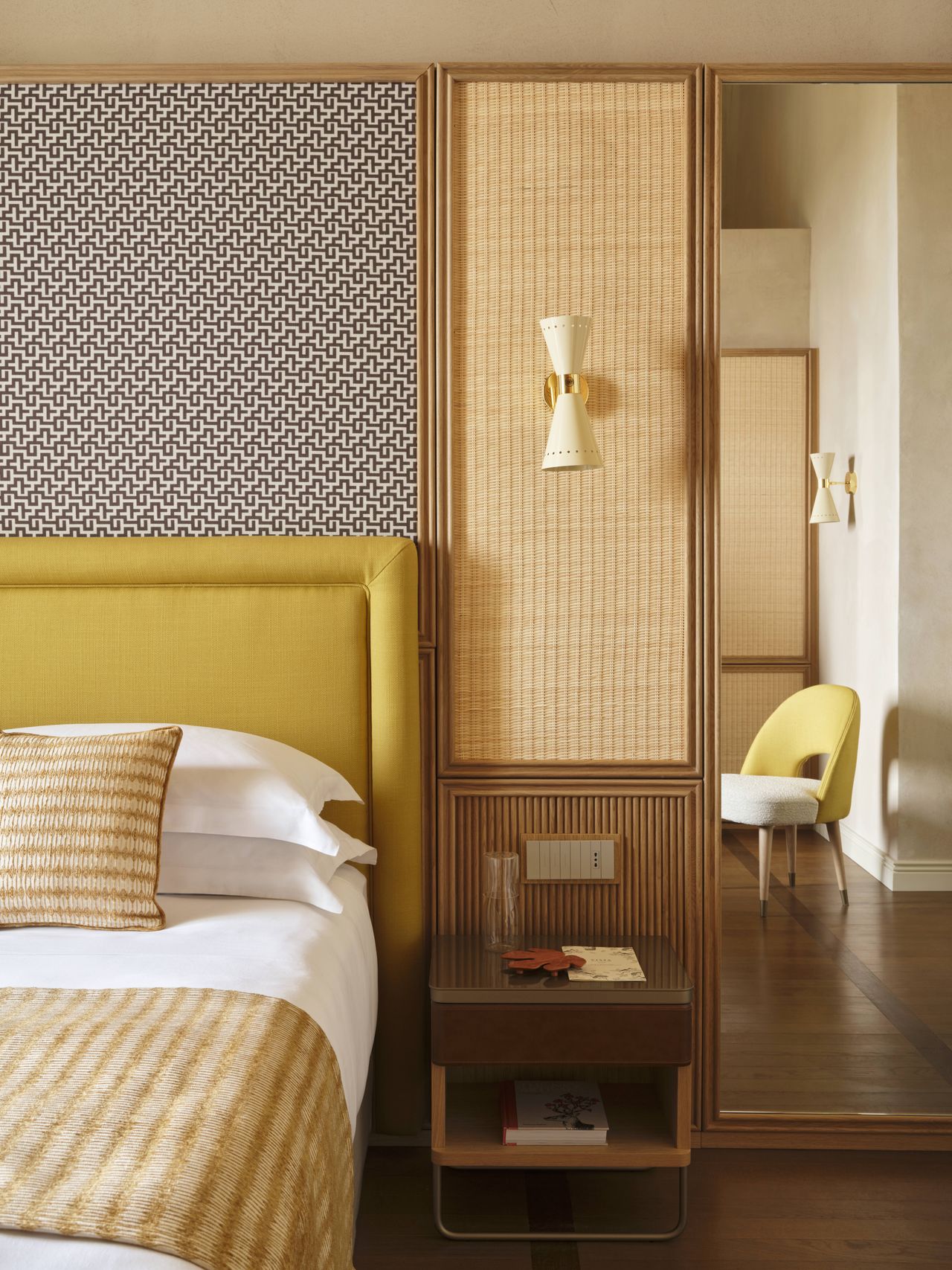 A design hotel with historic, vaulted architectural walls houses a selection of retro-inspired furniture, including colorful sculptural armchairs, layered wallpapers and panels, tiled flooring, eye-catching artworks, and wavy sofas, along with a panoramic rooftop bar with sun loungers.