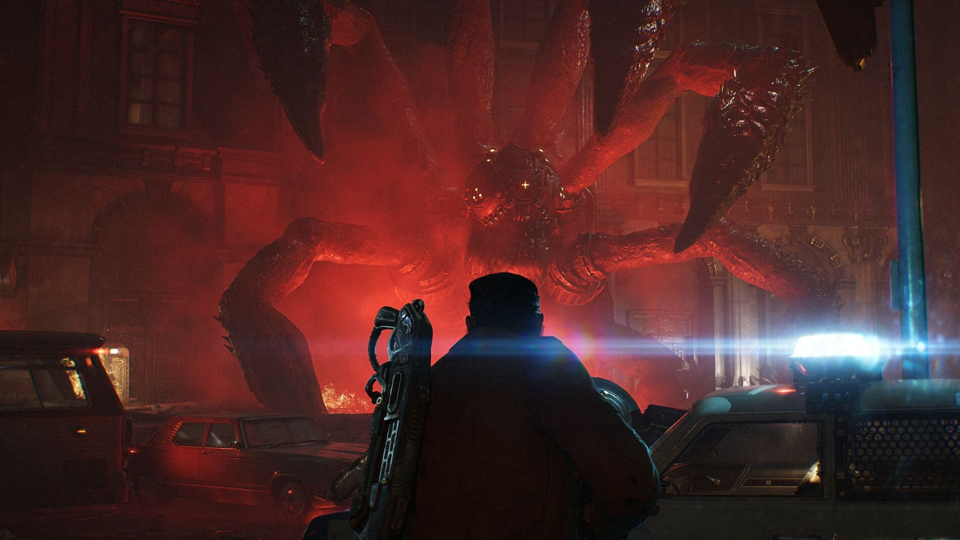 Screenshot from Gears of War: E-Day showing Marcus Fenix facing down a giant alien insect in dark streets illuminated by a red light.