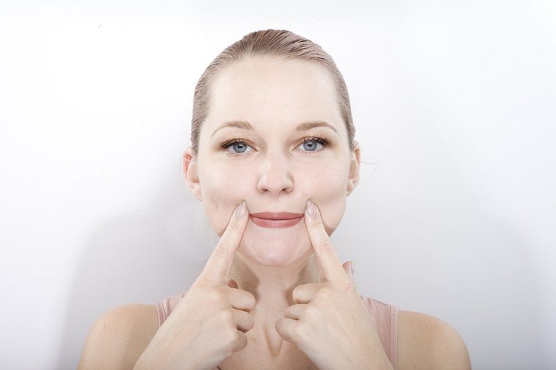 A woman performing a facial exercise.