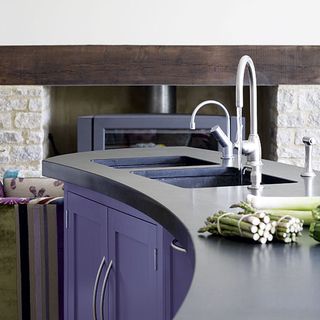 curved kitchen sink area with lavender colour pullout shelves and pipes