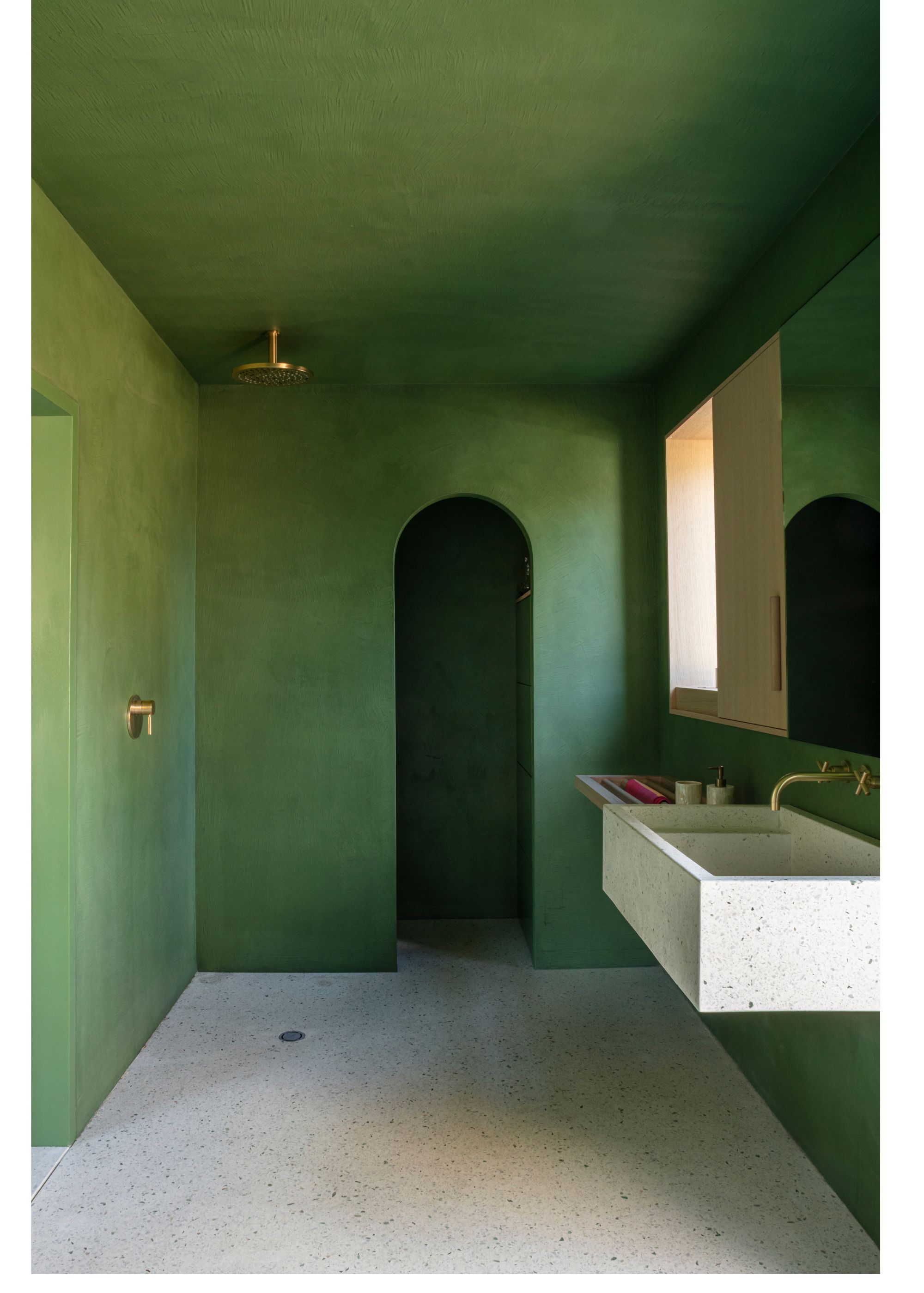 A bathroom with green walls, and white terrazzo flooring