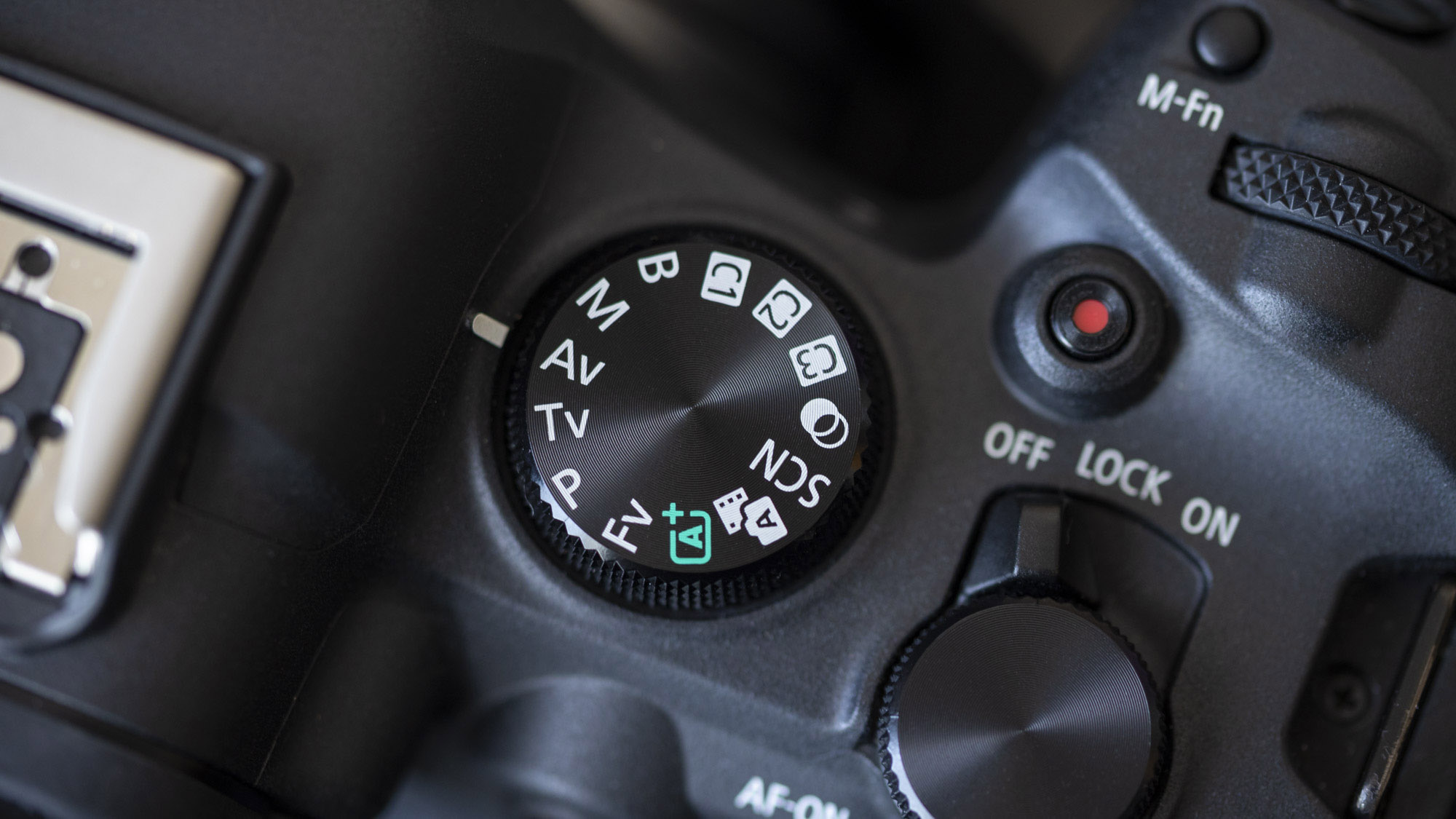 A close-up of the top of a Canon EOS R6 Mark II showing its mode dial without a locking button