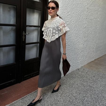 Annabel wears a gray and white dress, black slingbacks, and a bag.