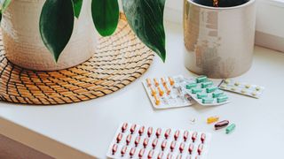 Selection of supplements and pills sitting on windowsill with potted plants, representing alternatives to CBT for menopause