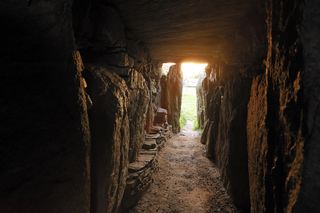 The entrance passage of the Bryn Celli Ddu tomb aligns with the sunrise at mid-summer, casting light on the stone-lined chamber within.