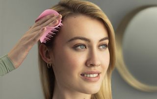 woman using a Tangle Teezer hairbrush to home treat dandruff