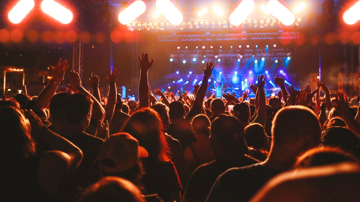 Concert crowd cheering, concert audience arms raised. Live entertainment concept of music festival crowd cheering for live music performance