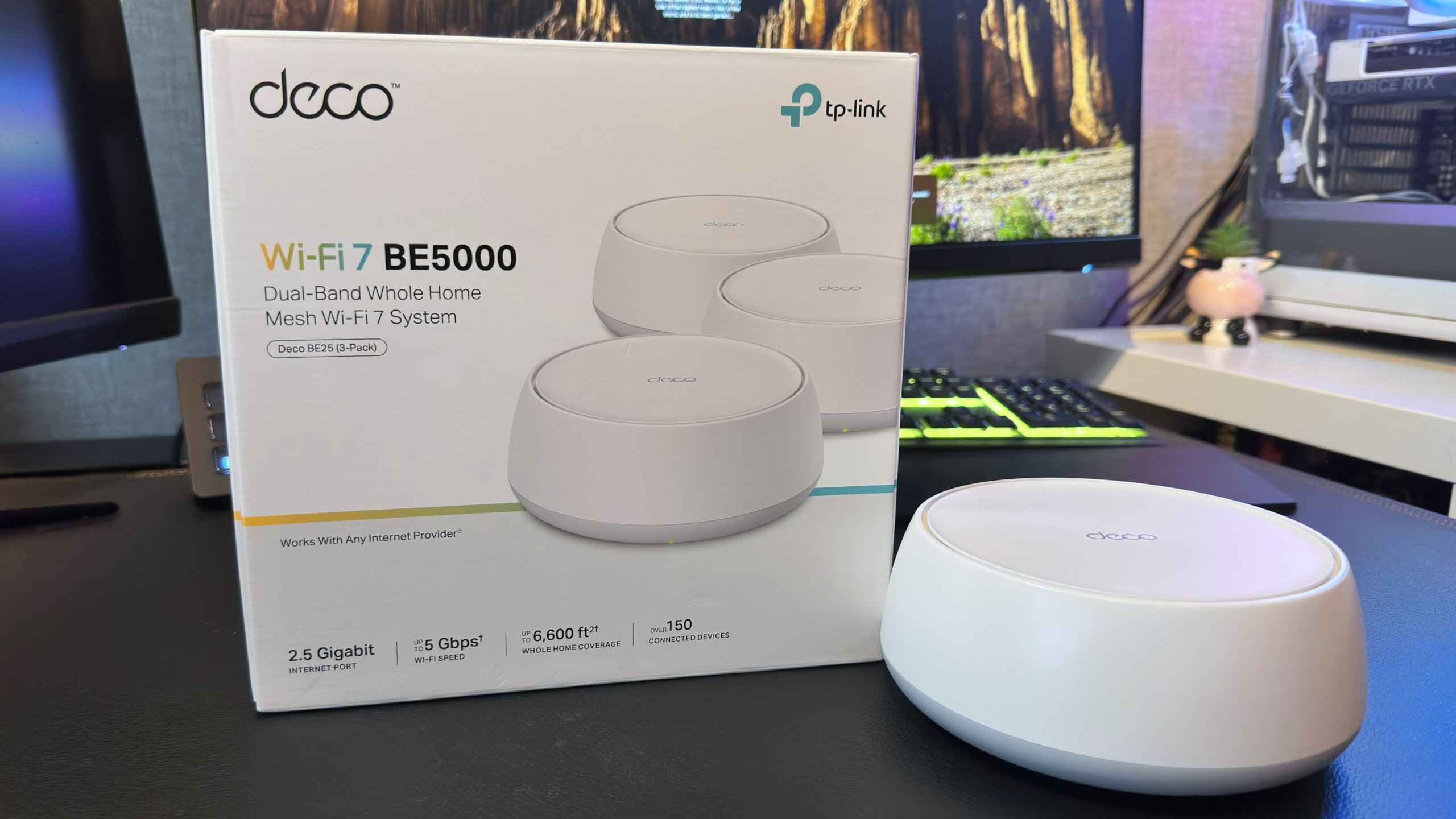 A photo of a TP-Link Deco BE25 mesh router next to its retail packaging.