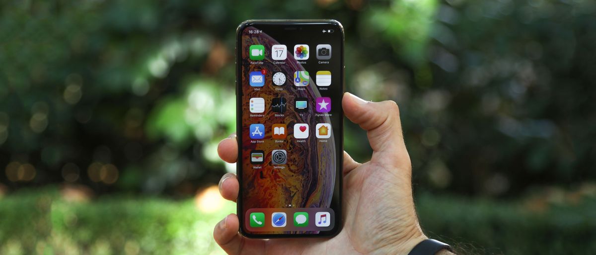 An iPhone XS Max in someone&#039;s hand, with the screen on