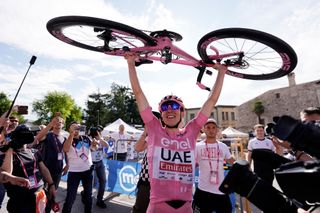 Tadej Pogačar holds his bike aloft after winning stage 20 of the Giro d'Italia