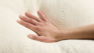 A hand pressed slightly into an off-white pillow