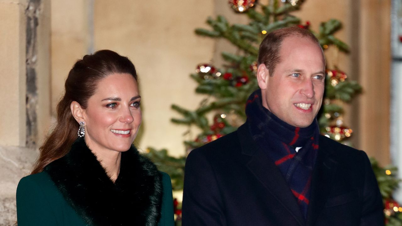 Kate Middleton wears a green winter coat with a large black fluffy collar and Prince William wears a large black overcoat and a tartan scarf