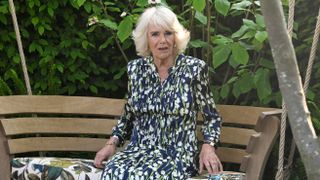 Queen Camilla sits on a bench in London Square Community Garden