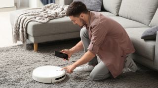 Man setting robot vacuum on rug