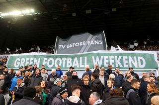Fans of Newcastle United hold up banners reading 'Tv Before Fans' and 'Green Football Weekend' during the Premier League match between Newcastle United and Luton Town at St. James Park on February 03, 2024 in Newcastle upon Tyne, England.