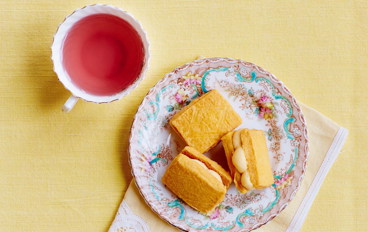 Custard cream biscuits on a plate with a cup of tea