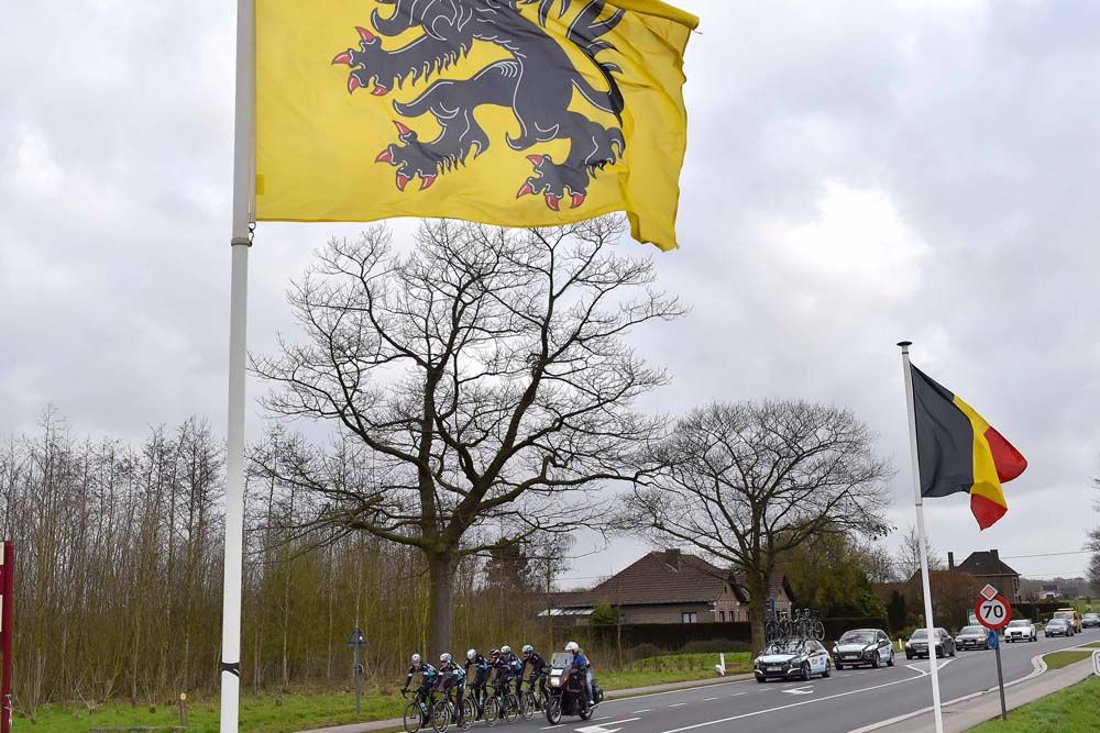 The Etixx-QuickStep team rides past Belgian and Flemish flags