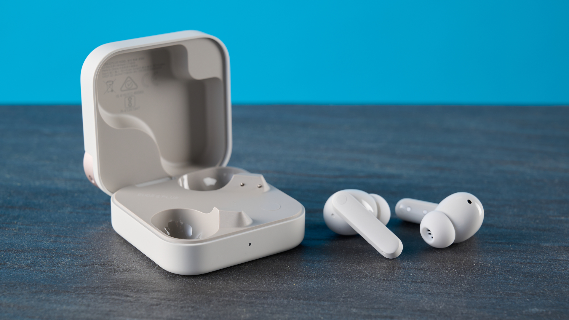 CMF Buds 2 Plus in light gray photographed in front of a blue background