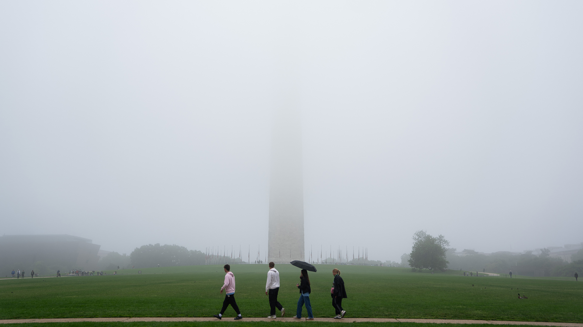 A group of people walk past the cloud-wrapped Washington Monument on Memorial Day in Washington, D.C.