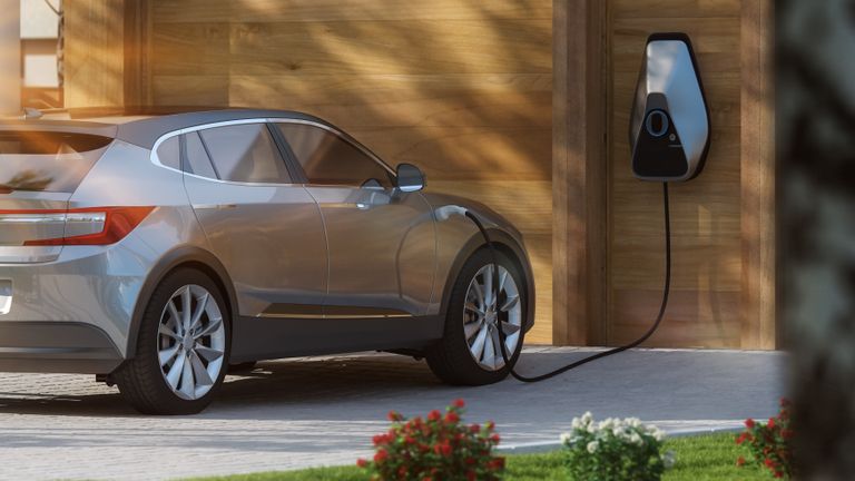 electric car charging at home with an EV car on the driveway linked to an electric port