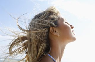 A woman tilts her face toward the sun.