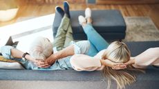 A retired couple sit back on their sofa with their feet up.