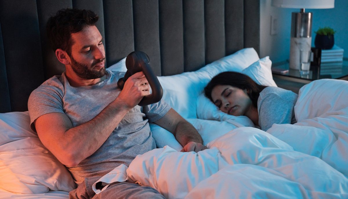 Man using massage gun in bed