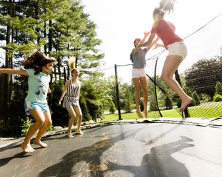 teenage girls trampolining in garden