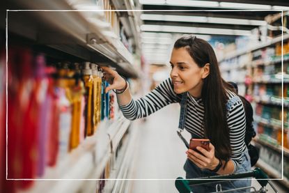 woman looking closely at items in supermarket aisle