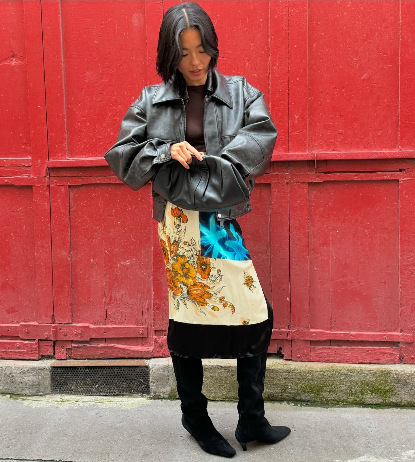An image of @_yanyanchan wearing black suede slouchy boots with a floral maxi skirt and a leather jacket.