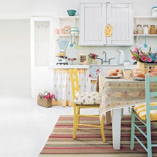 white kitchen diner with traditional furniture and appliances and coloured chairs
