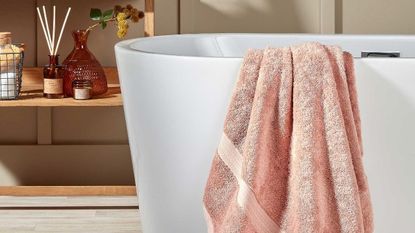 Blush pink twoel draped over white freestanding bath