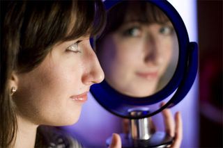 A teen girl looking in the mirror.