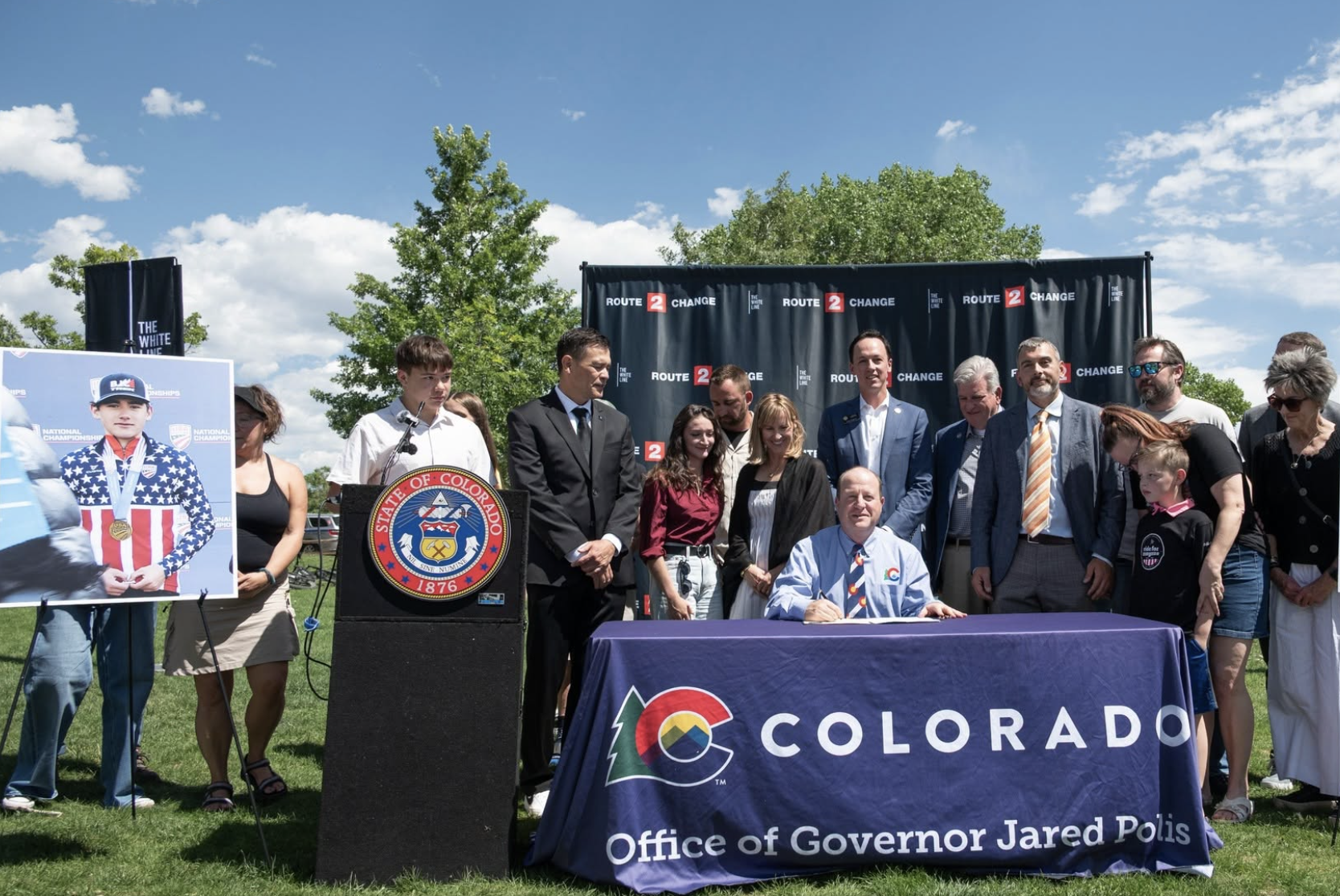 Governor Polis (seated) is joined by advocates and legislators at Valmont Bike Park for the signing of SB26-132 on June 4, 2026