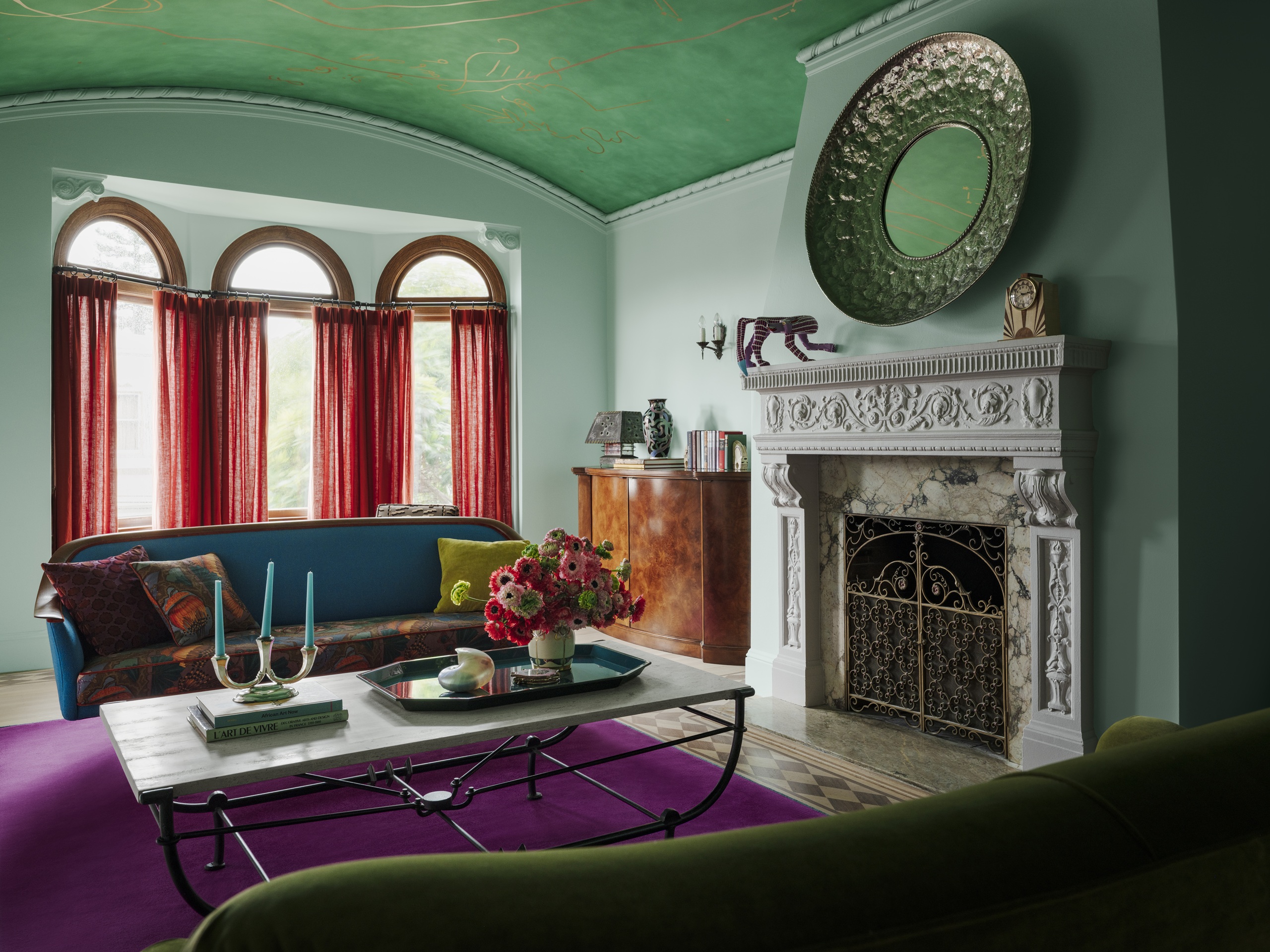 a blue and green living room with red curtains and a purple rug