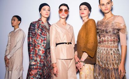 Models wear floral coat and skirt, creme blazer, rust knit and beige dress