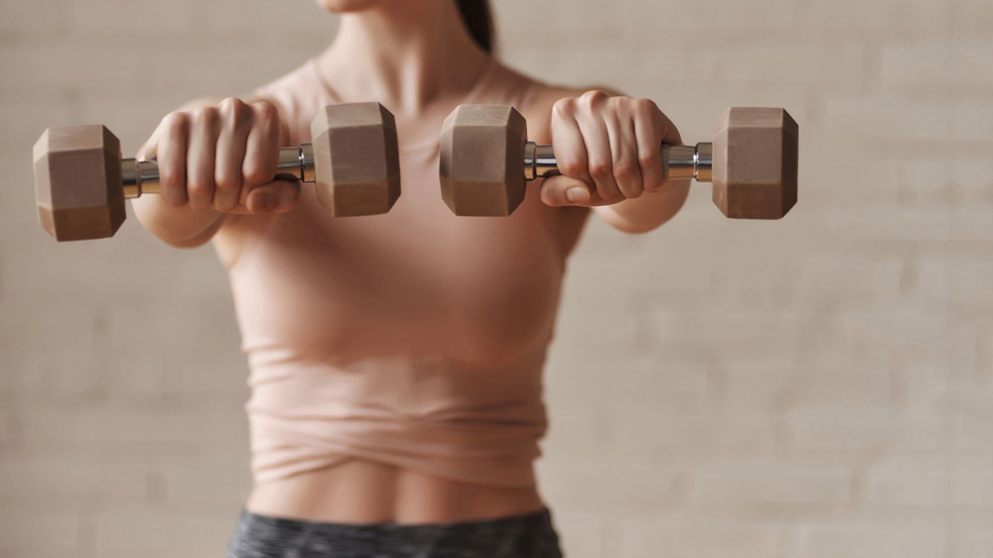 Best 10-minute arm workouts: A woman doing an arm workout with weights at home