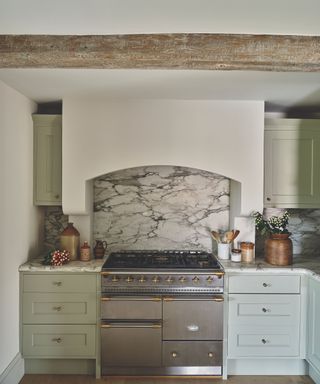 kitchen with large cooker and pale green cabinetry and light grey marble