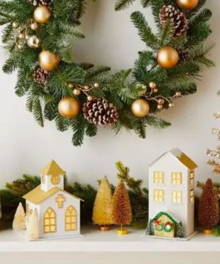 A Christmas wreath above a mantel against a white wall.