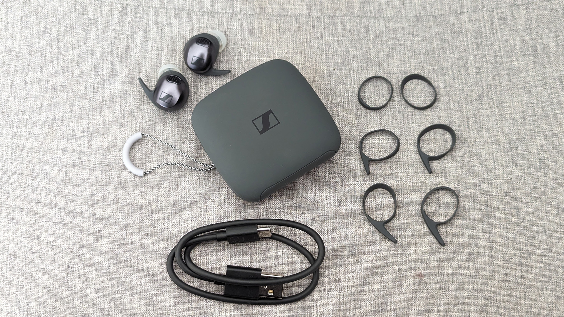 Sennheiser Momentum Sport in-ear headphones showing earbuds, case and accessories